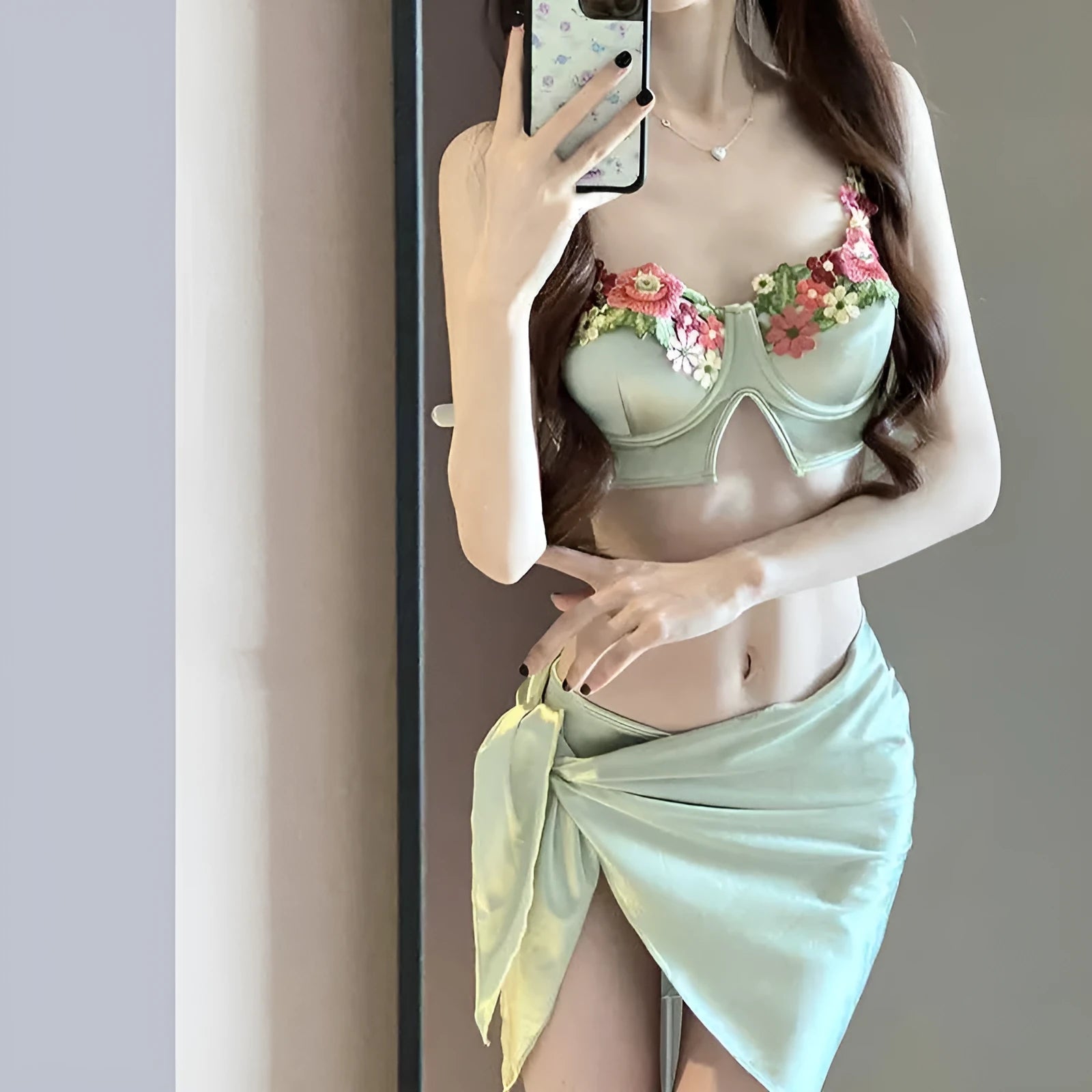 Green three-piece women's bikini swimsuit with triangle top, briefs, and skirt