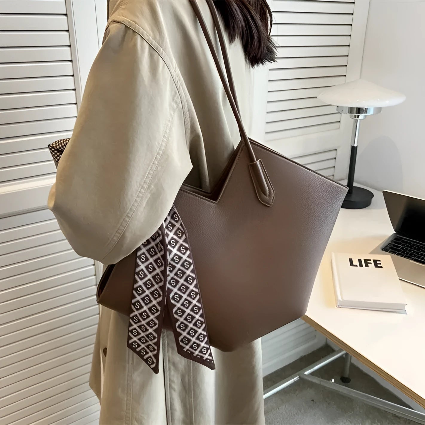 Women's large beige PU shoulder bag with square shape and long strap on a plain background.