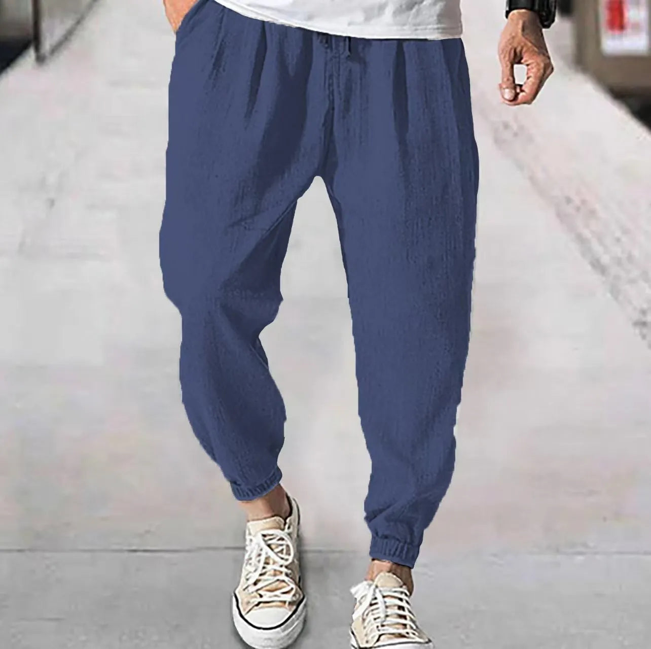 Man wearing loose light-coloured cotton trousers with elasticated ankle cuffs, showing front and side views.