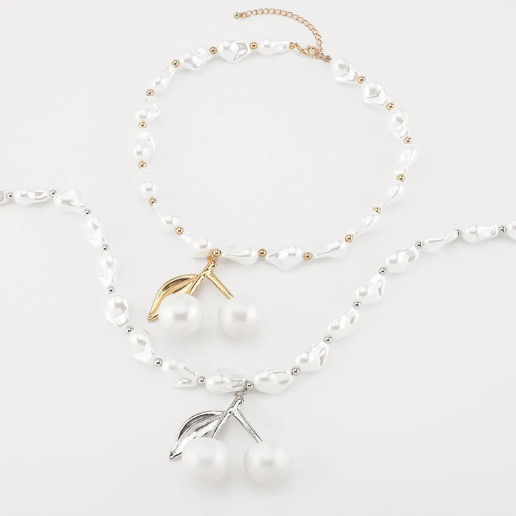 Gold electroplated cherry fruit pendant on an adjustable white pearl chain necklace for women.