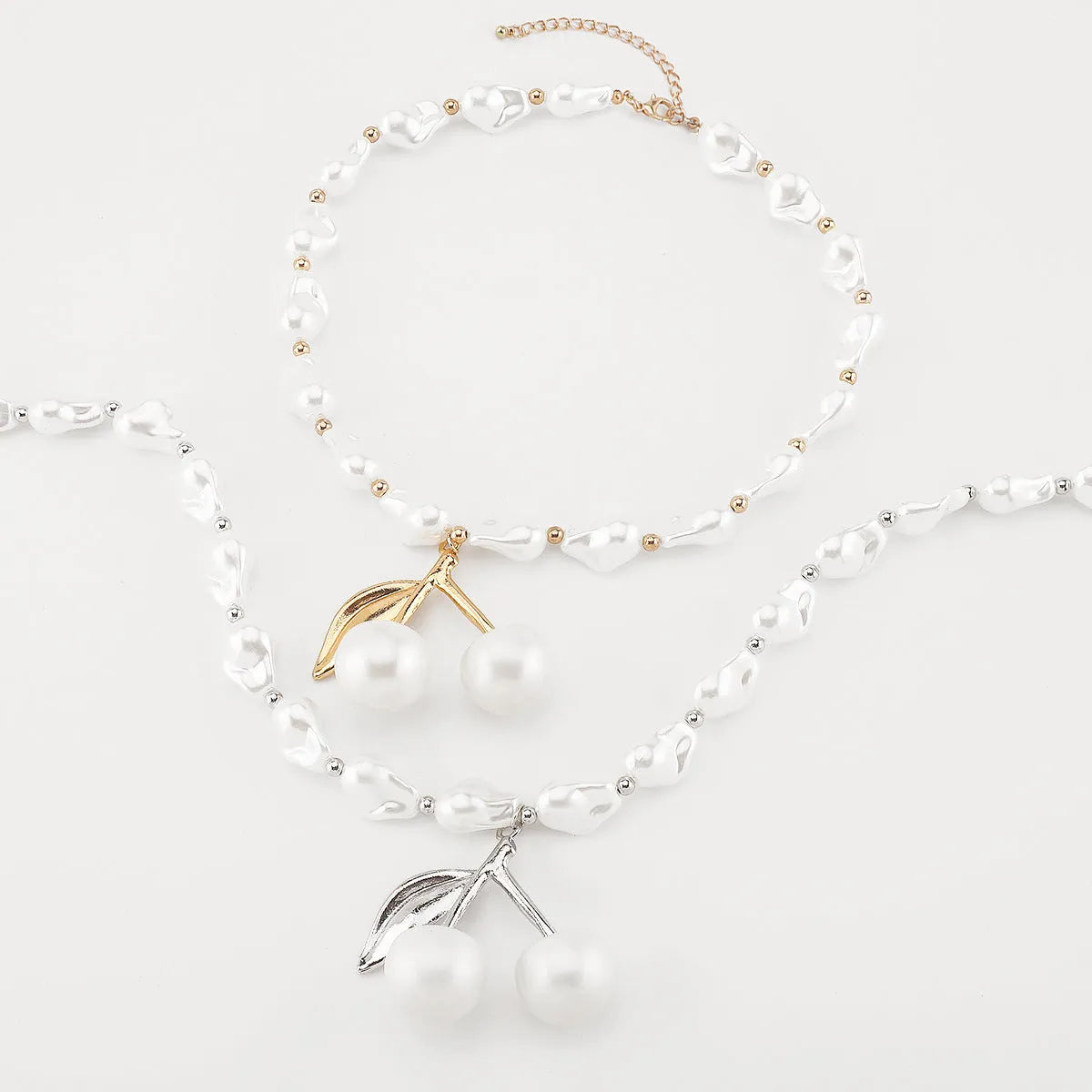 Gold electroplated cherry fruit pendant on an adjustable white pearl chain necklace for women.