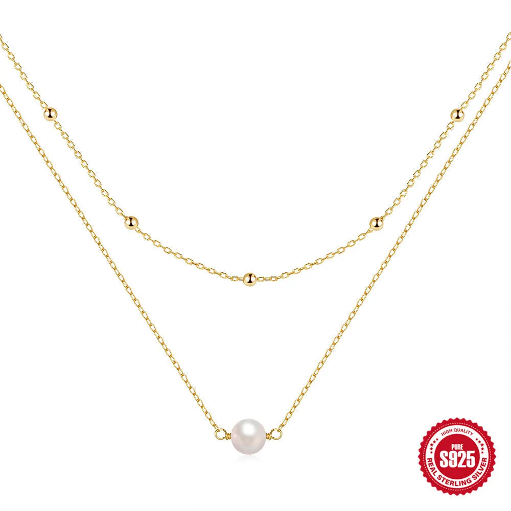 Close-up of a women's double layer sterling silver necklace with two round freshwater pearls on a geometric pendant.
