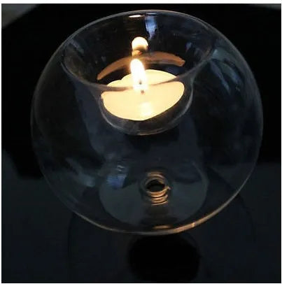 Clear round handmade hollow glass candle holder sphere on a table.