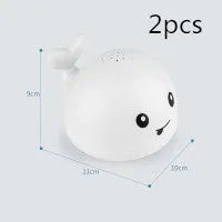 White and blue electric whale bath toy spraying water with flashing lights on a bathroom surface.