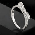 Silver bow-shaped ring with sparkling rhinestones and zircon crystals on a finger.