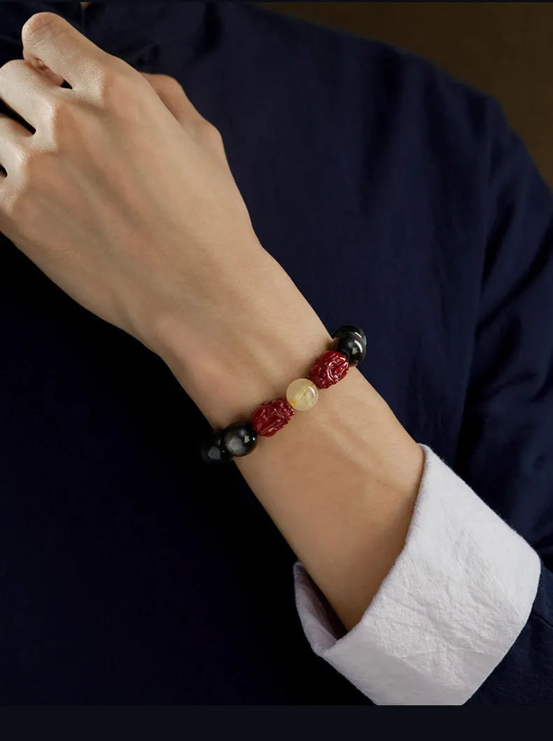 Carved cinnabar beads bracelet with gold obsidian animal zodiac design on a gift box.