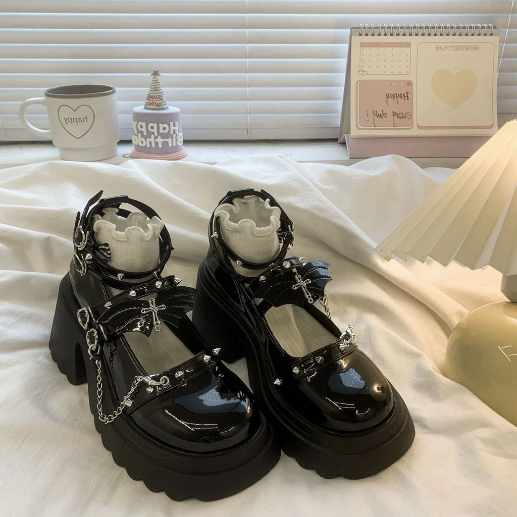 Black patent leather bat cosplay Lolita shoes with metal chain buckle and chunky heel on white background