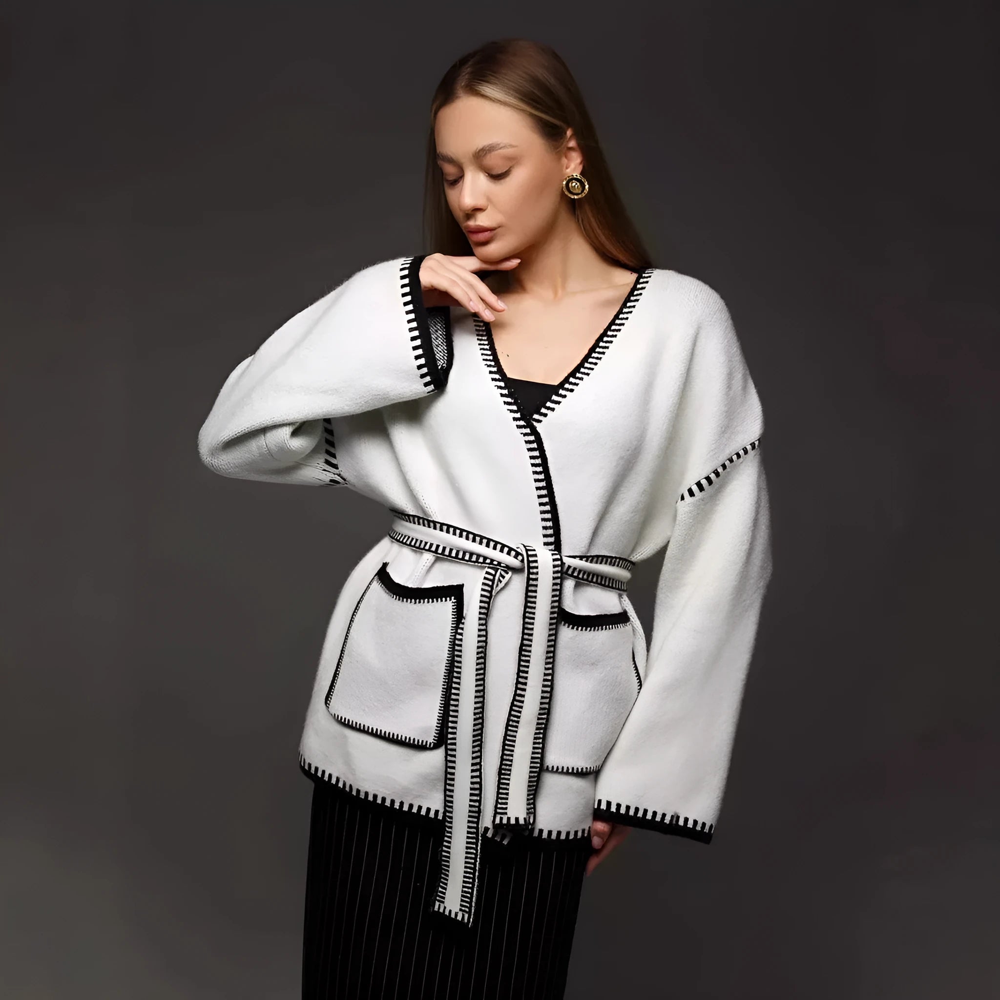A white lace-up knitted cardigan with long sleeves on a hanger, showing the front tie detail.
