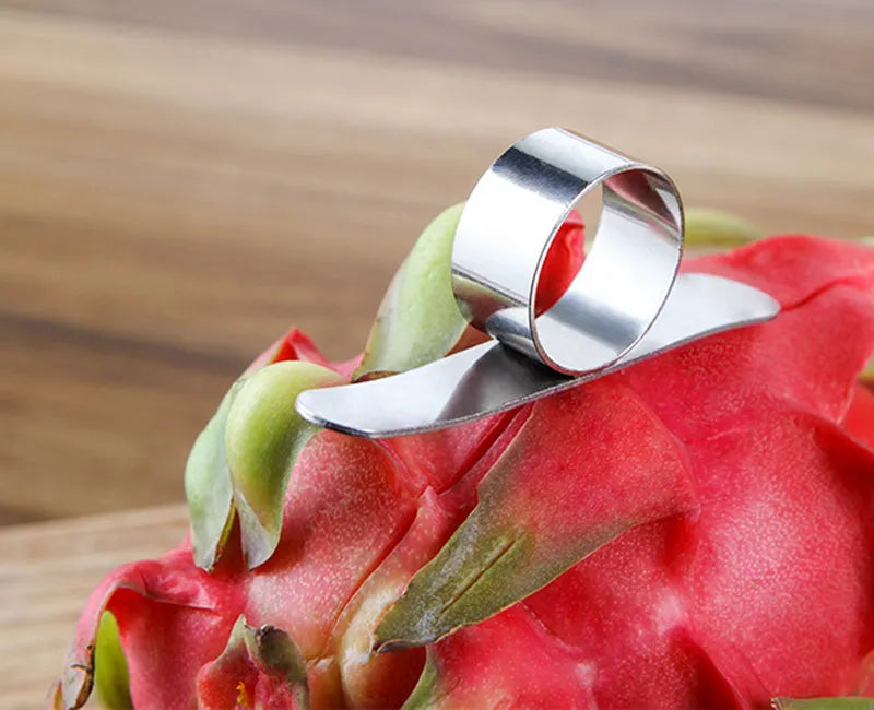 Silver stainless steel finger ring fruit peeler for oranges and pomelos on a kitchen surface.