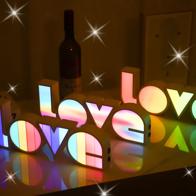 Rainbow-style plastic LED decorative light spelling LOVE, shown on a table.