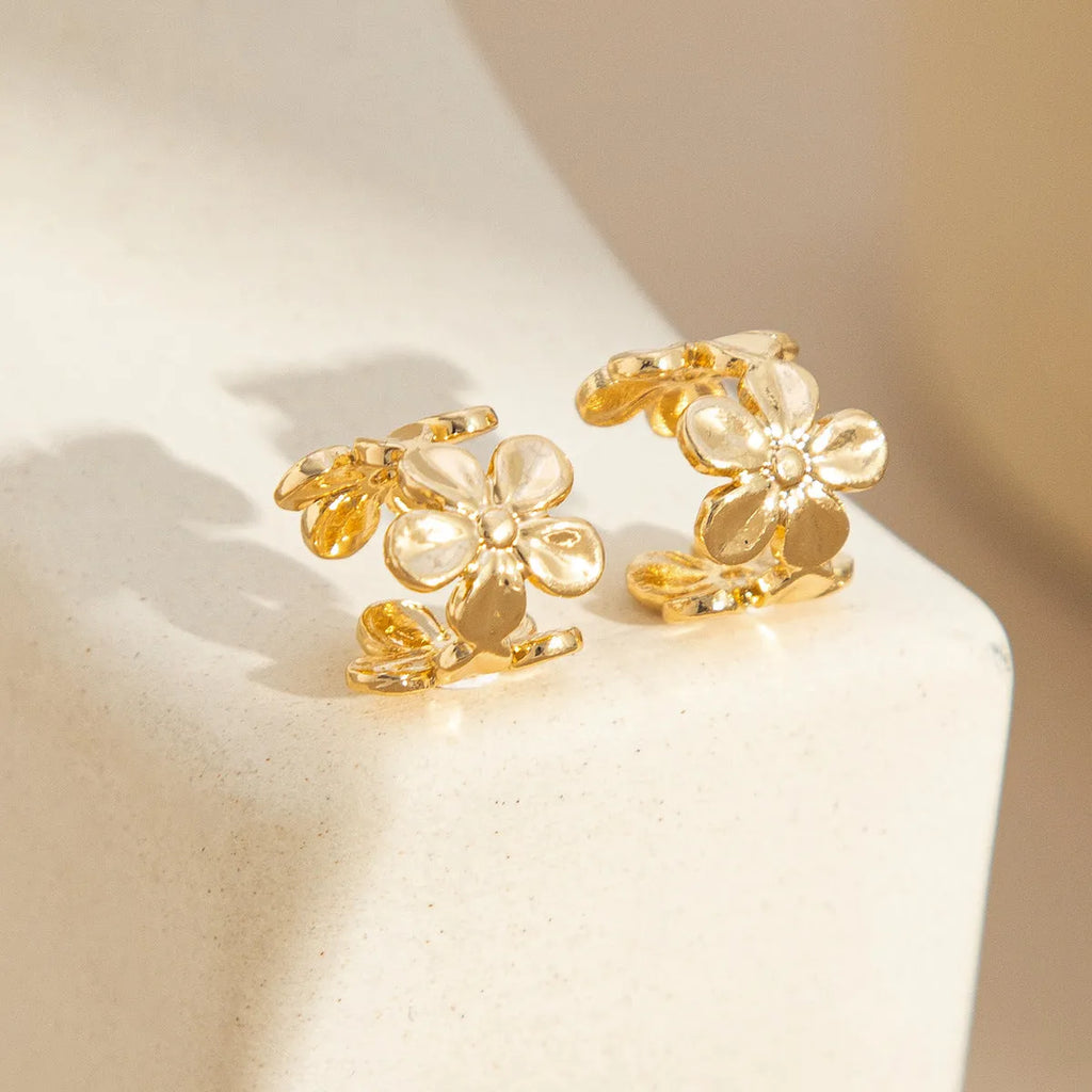 Women's gold starfish and conch shell drop earrings on a white background.