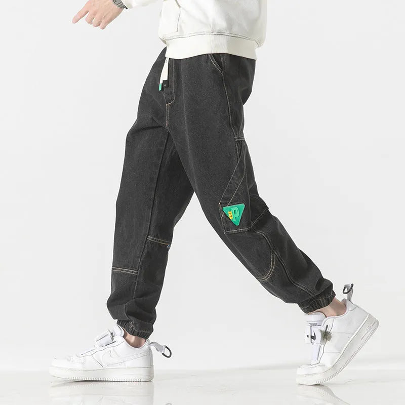 Men's loose-fit tapered cotton trousers in black, shown on a hanger