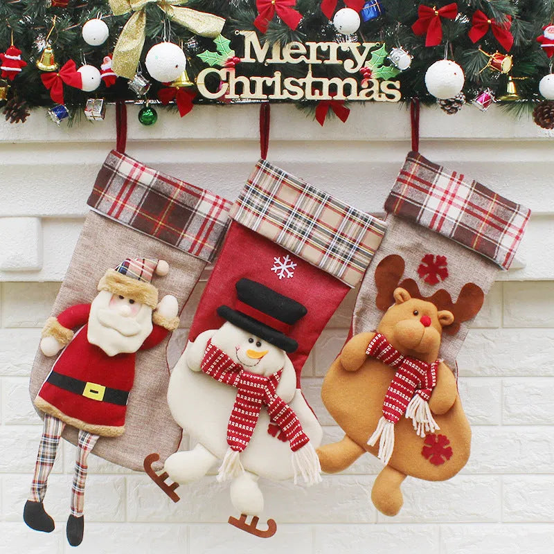Three Christmas sock gift bags with old man, snowman, and elk designs on a light background