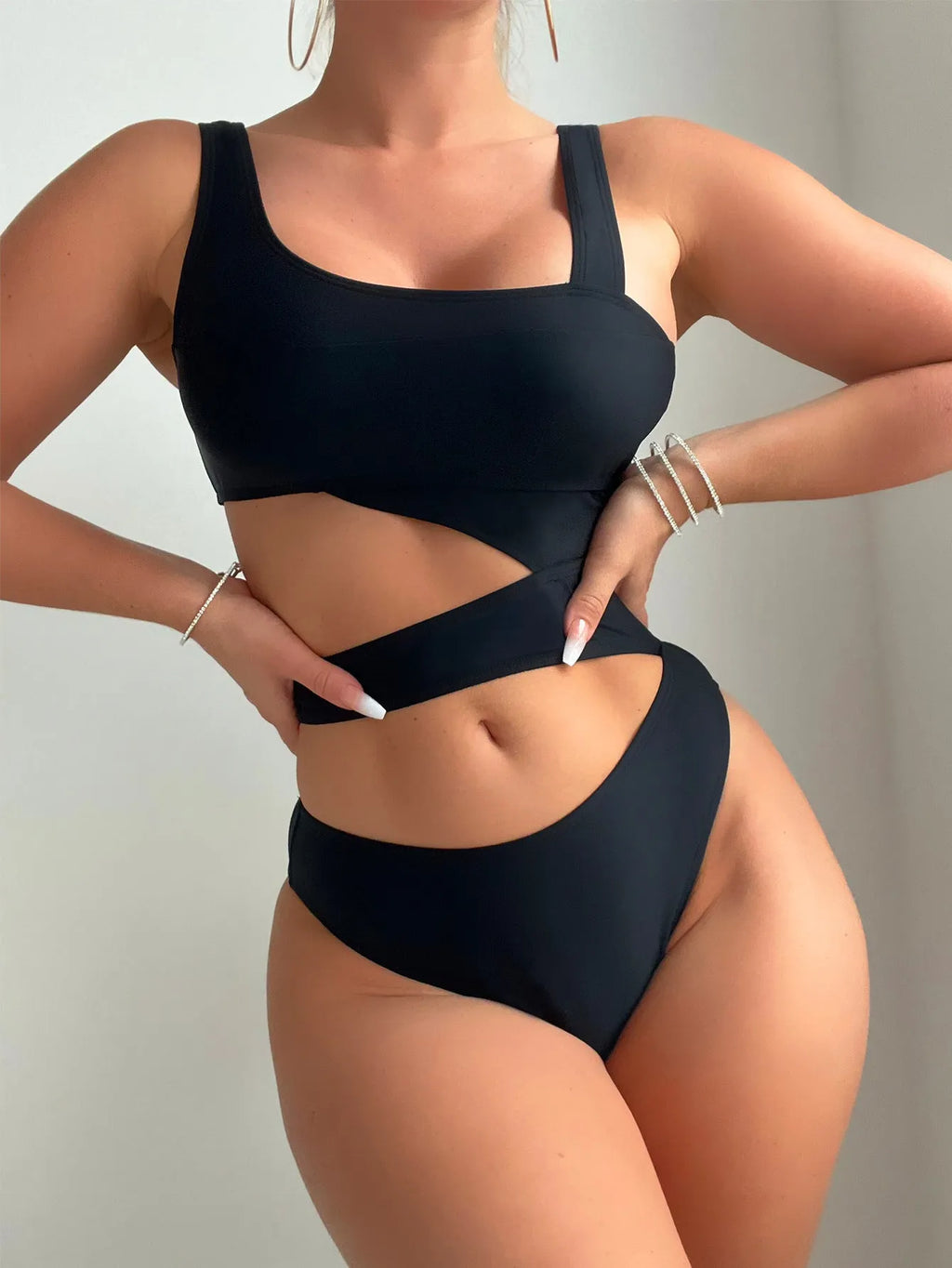 Black hollow high cut one-piece swimsuit on hanger showing sleeveless design