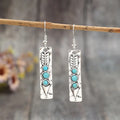 Long silver geometric drop earrings with blue turquoise stone inlays on a retro-style setting.
