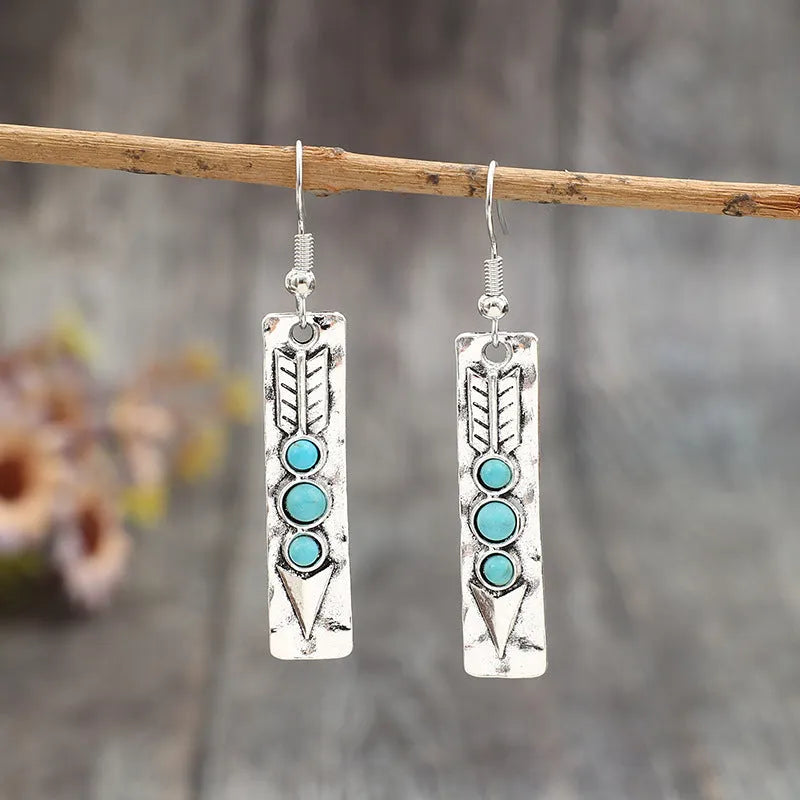 Long silver geometric drop earrings with blue turquoise stone inlays on a retro-style setting.