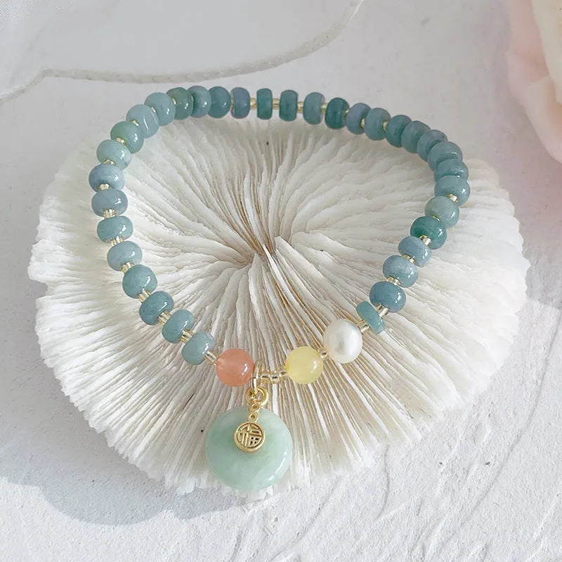 Blue-toned jade bracelet with gourd and peace buckle charms and strawberry quartz accents