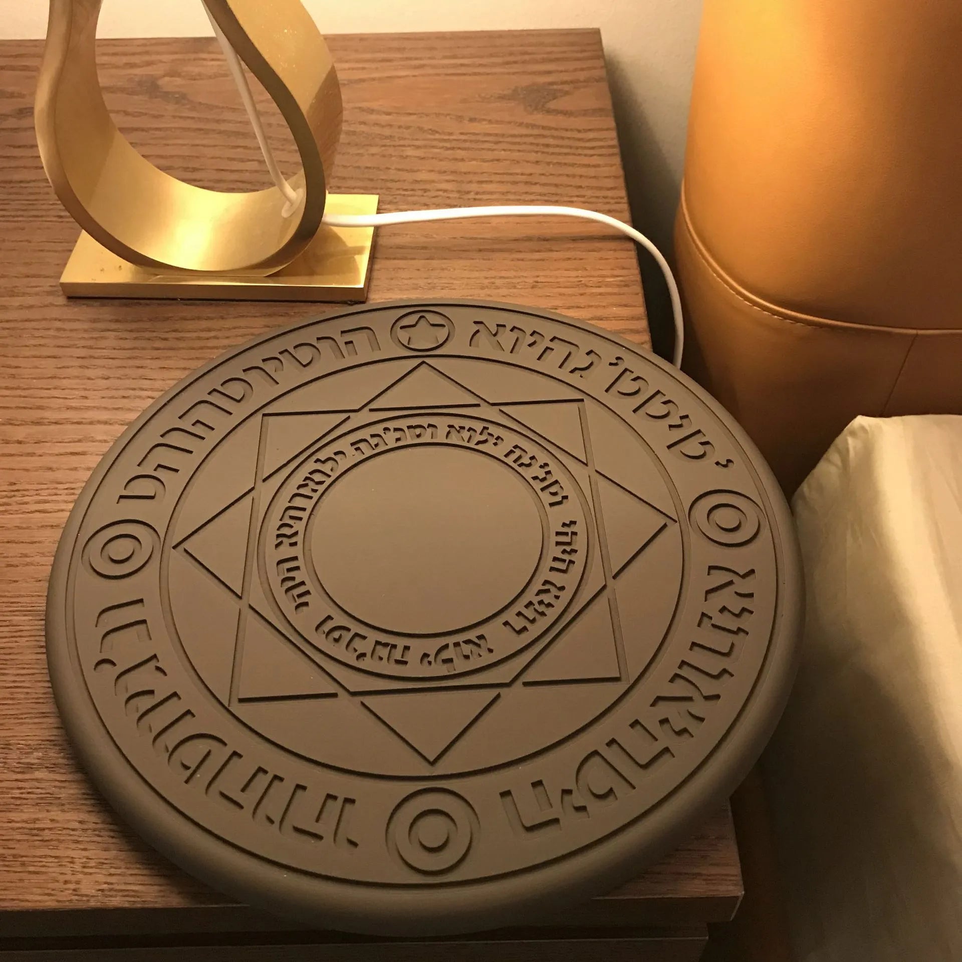 Square 25cm 10W fast wireless phone charger with glowing magic array pattern in black on a desk