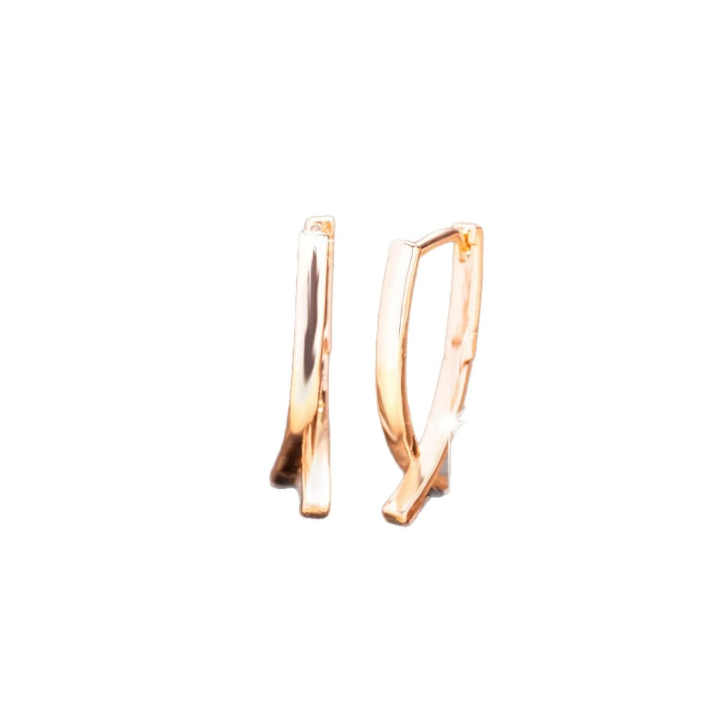 A pair of rose gold coloured cross-shaped earrings made from copper on a plain background.