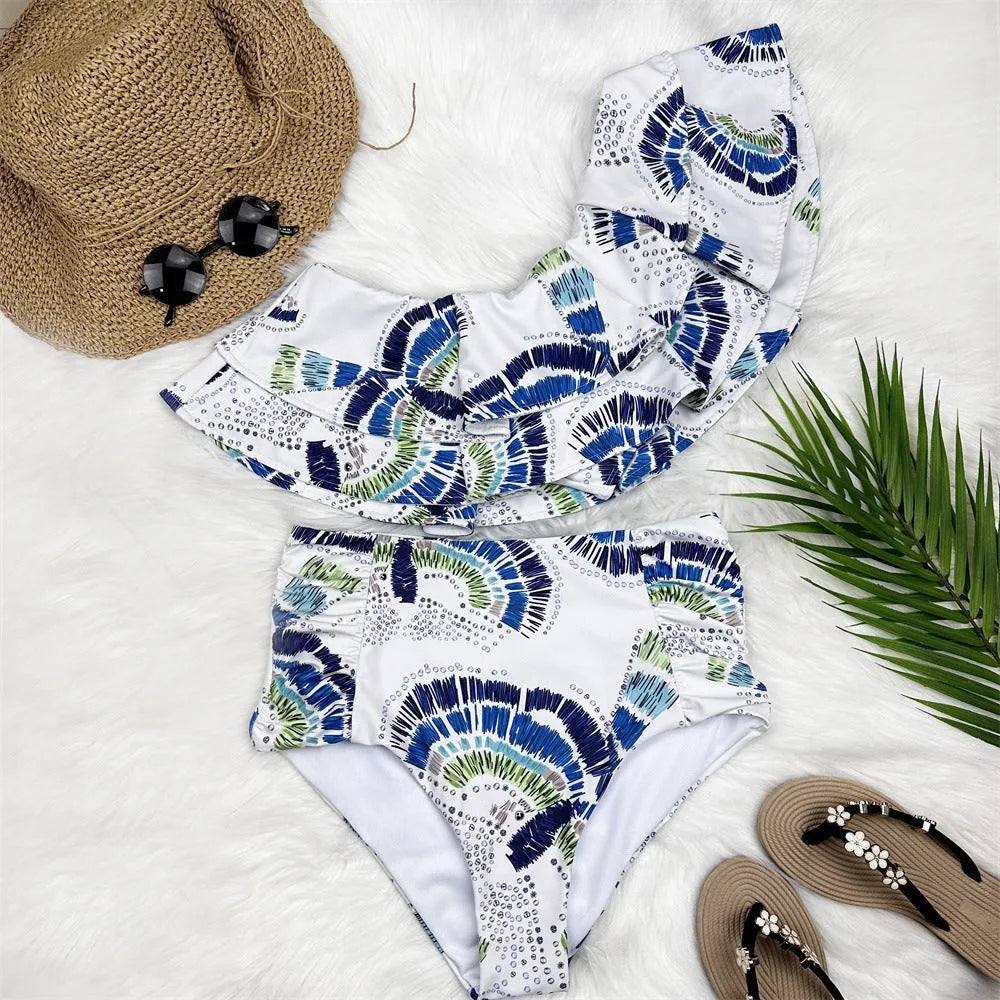 White women's one-shoulder swimsuit with a layered lotus leaf design skirt and high leg split.