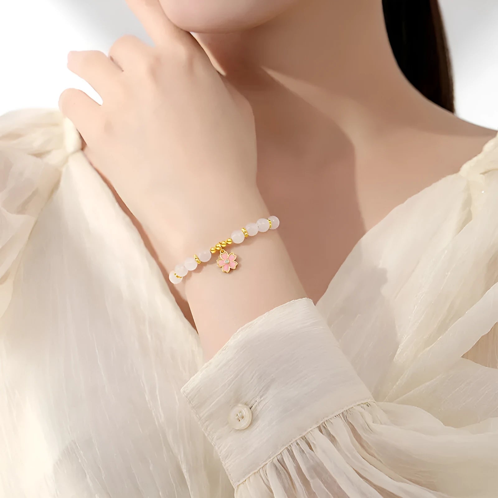 Close-up of a women's pink cherry blossom pendant and Hetian jade bead bracelet made from S925 silver.