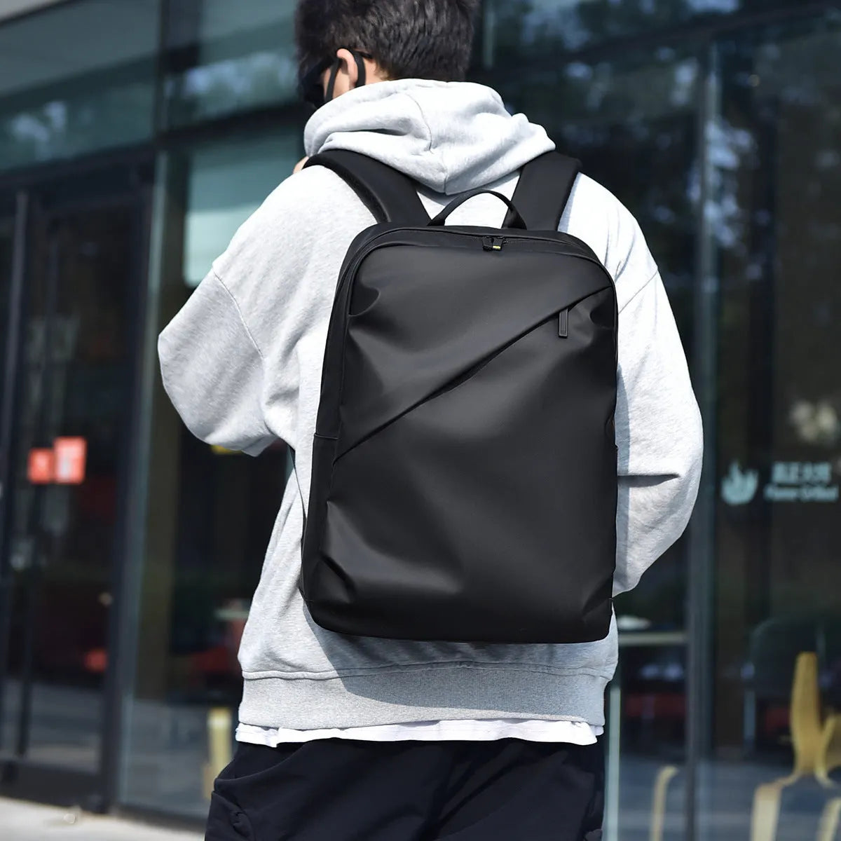 Large black waterproof PU leather computer backpack with simple design and sewing thread detailing