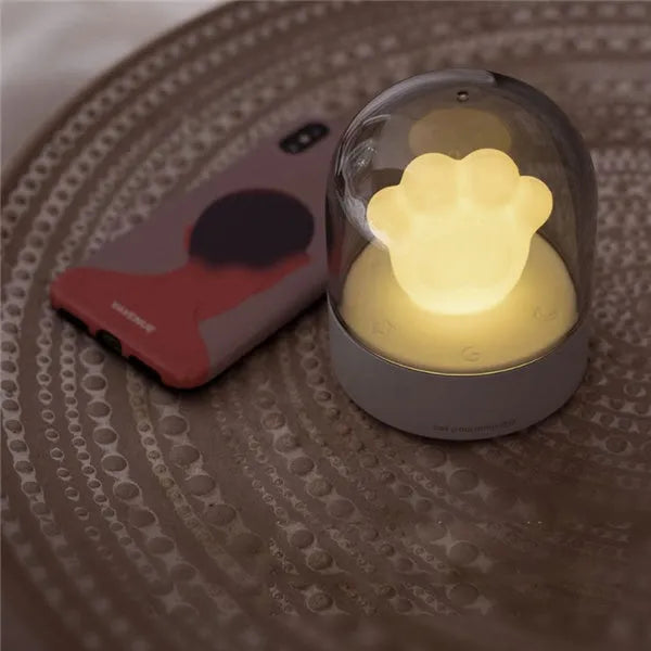 Cute grey or pink cat paw shaped USB rechargeable night light with music box on a desk.