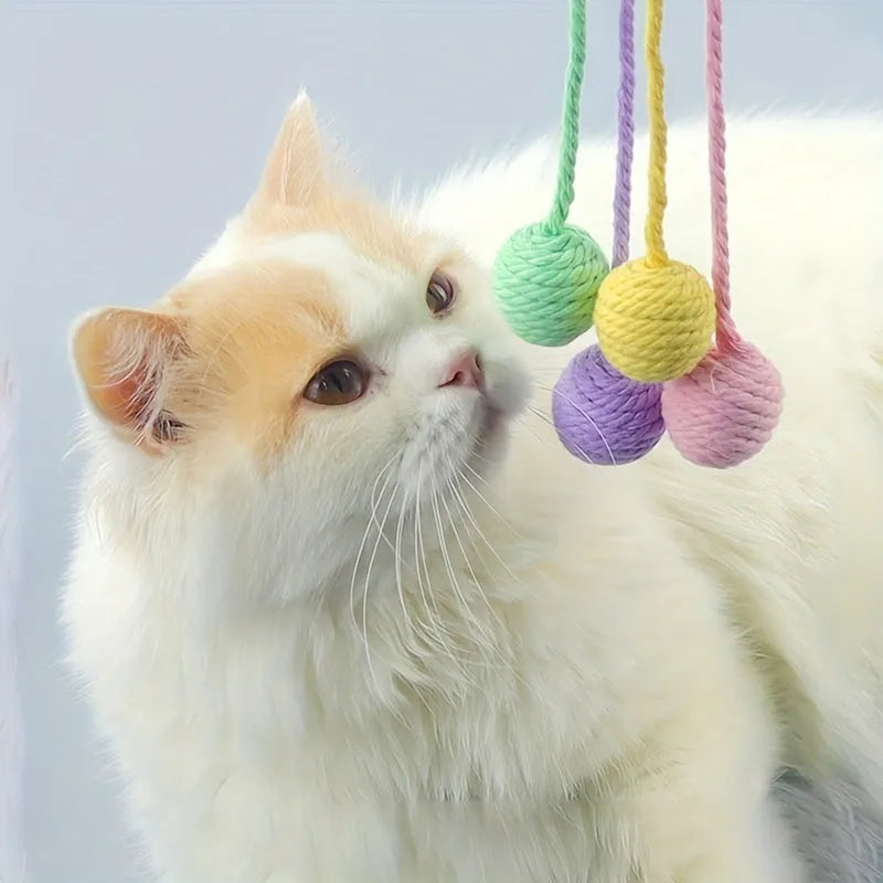 Cat toy ball with integrated rope and bell in green pink purple yellow colours