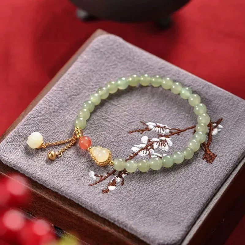Jade women's bracelet with gold-plated fu character and a central gourd charm on wrist.