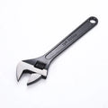 High carbon steel adjustable open-end wrench with black finish on a workbench.