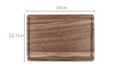 Solid black walnut wood chopping board with a deep perimeter groove and a side handle, shown as a serving tray.