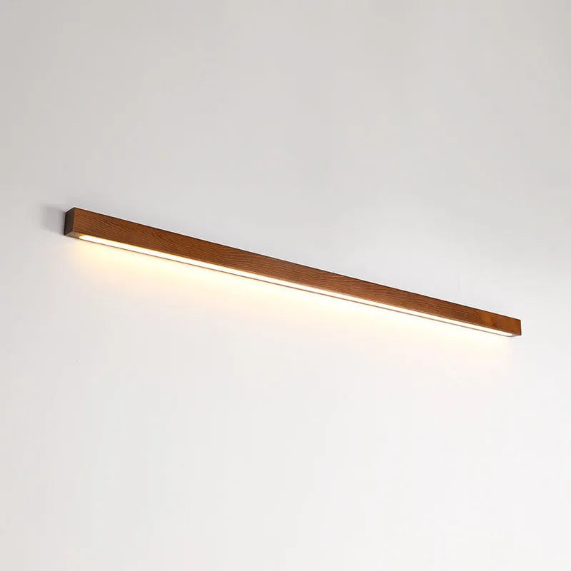 Walnut-coloured wooden log strip LED wall lamp with acrylic diffuser in minimalist design.