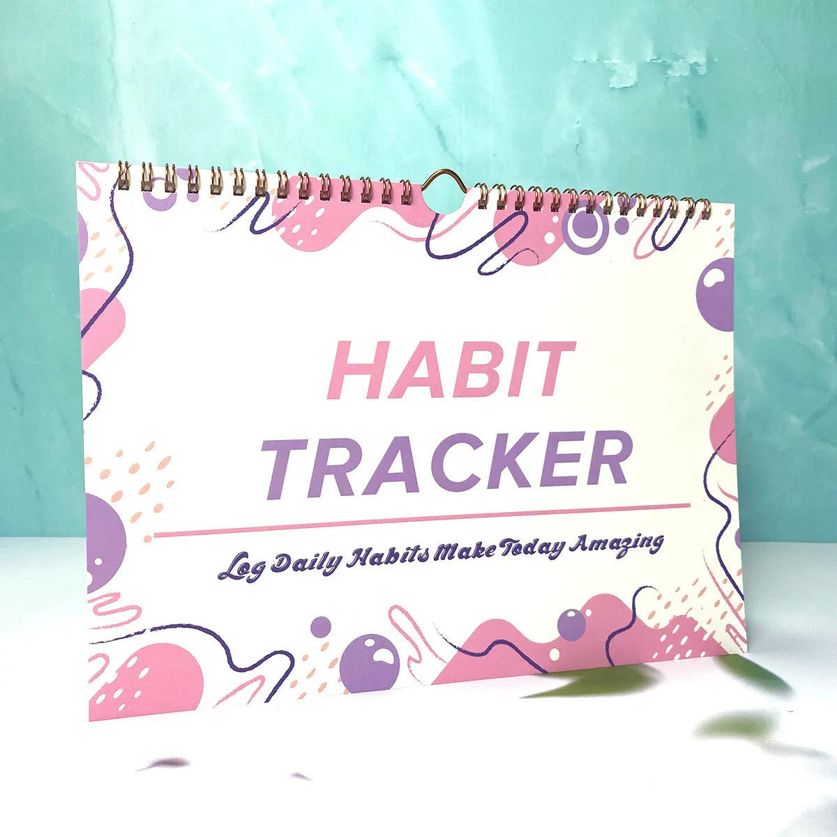 A5 habit tracking planner book open on a table, showing interior pages for schedule recording.