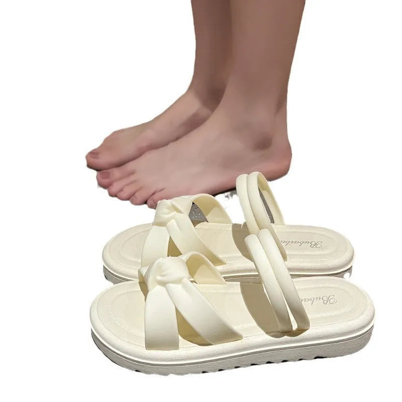 Women's black PVC sandals with soft back, floral detail, and a thick height-increasing sole.