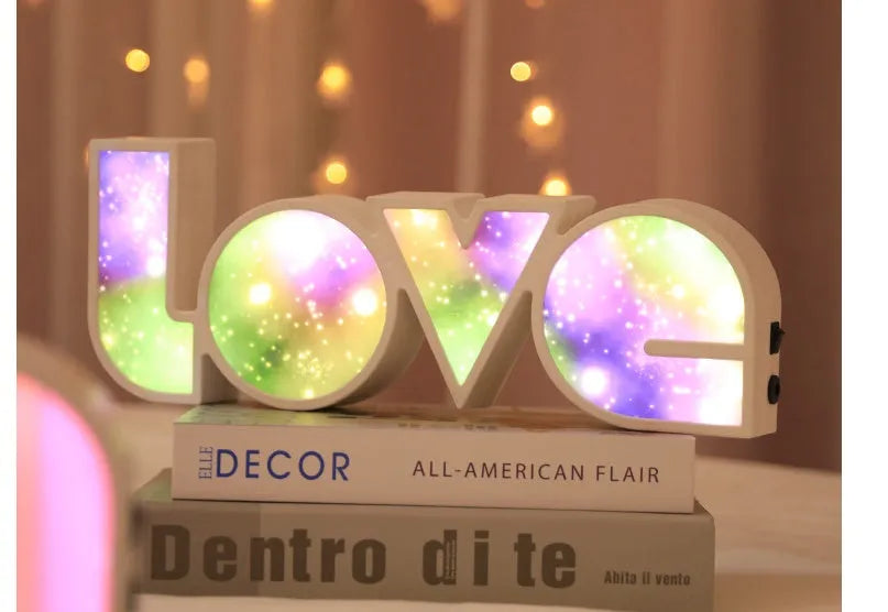 Rainbow-style plastic LED decorative light spelling LOVE, shown on a table.