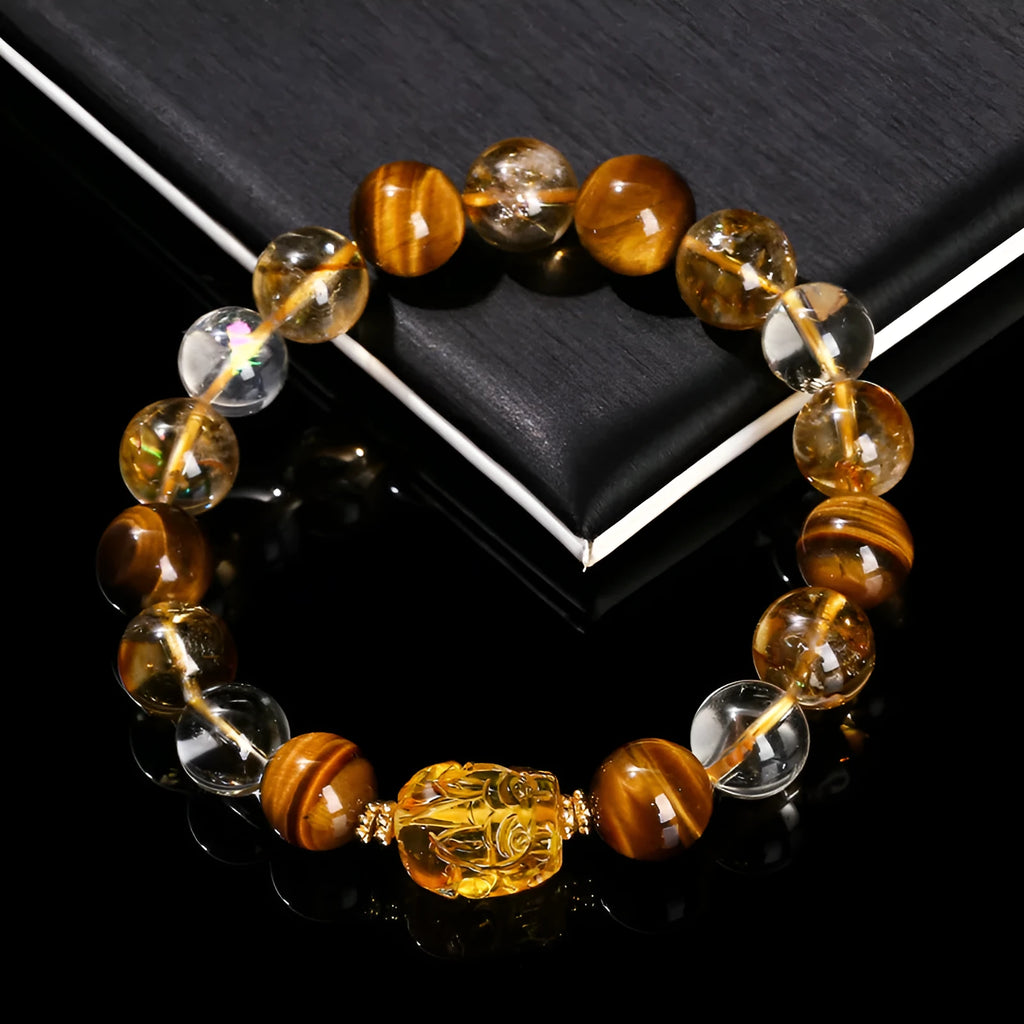 Close-up of a yellow tiger's eye and citrine bead bracelet with a geometric pi xiu charm on a wrist.