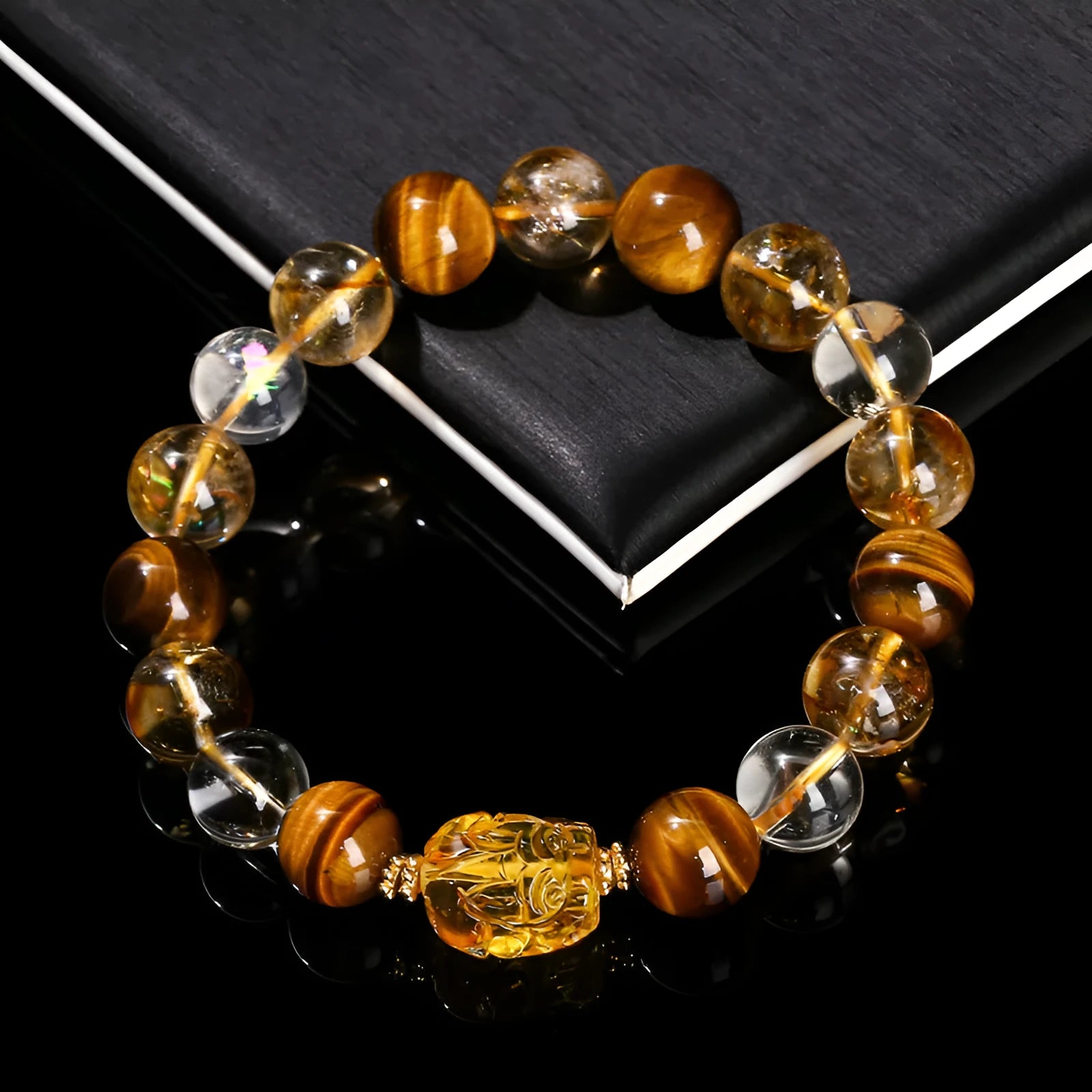 Close-up of a yellow tiger's eye and citrine bead bracelet with a geometric pi xiu charm on a wrist.