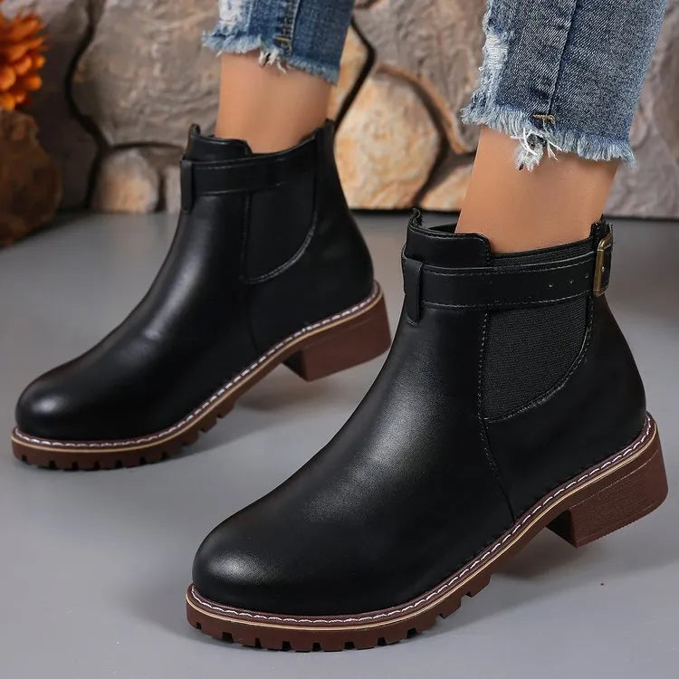 Black ankle boots with round toe and belt buckle decoration, showing rubber sole and waterproof artificial PU upper