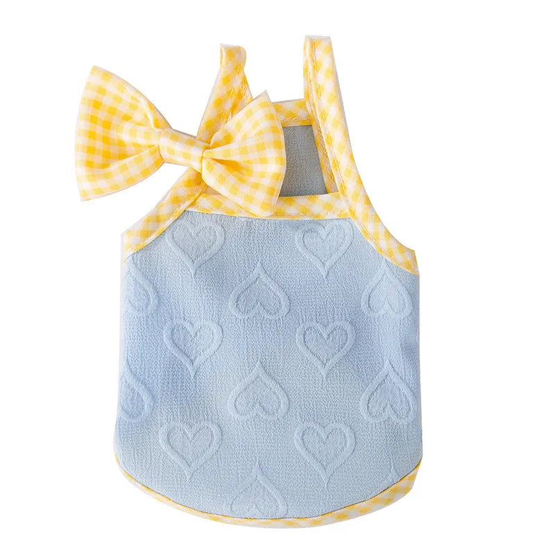 Small dog wearing a blue elastic vest with heart and bow details and adjustable suspenders.
