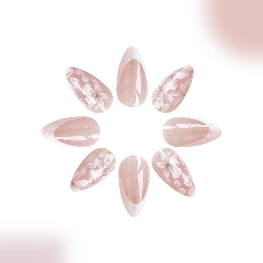 Short almond French style press-on nails with glitter accents and powder flower design on white background