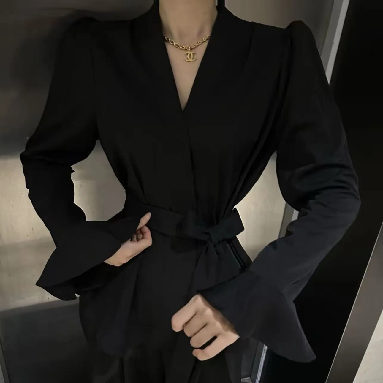 Women's black French-style shirt with an irregular collar and long bell sleeves.