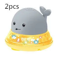 White and blue electric whale bath toy spraying water with flashing lights on a bathroom surface.