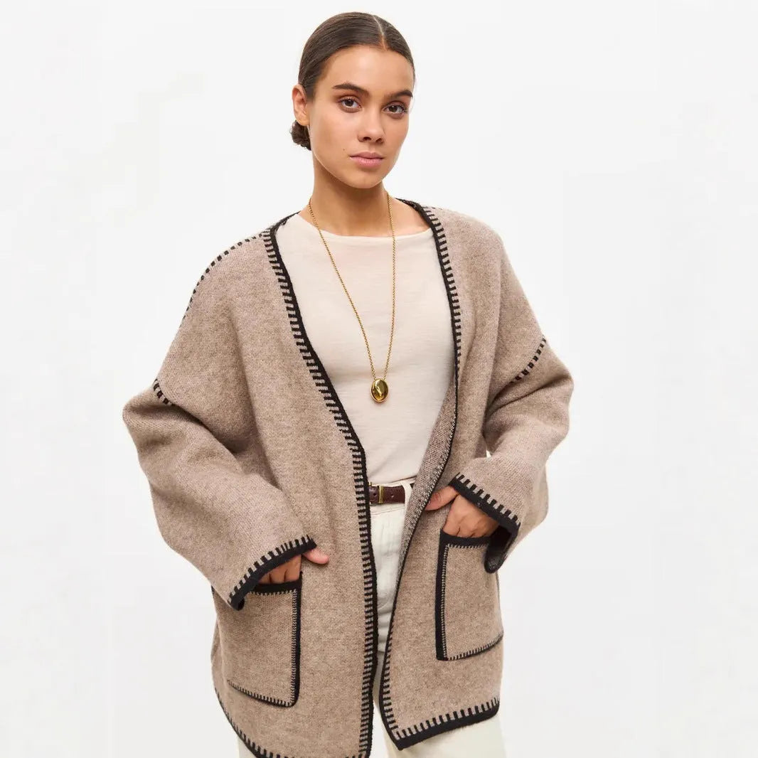 A white lace-up knitted cardigan with long sleeves on a hanger, showing the front tie detail.