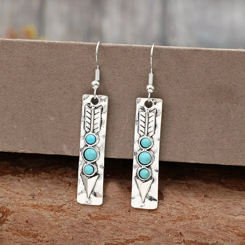 Long silver geometric drop earrings with blue turquoise stone inlays on a retro-style setting.
