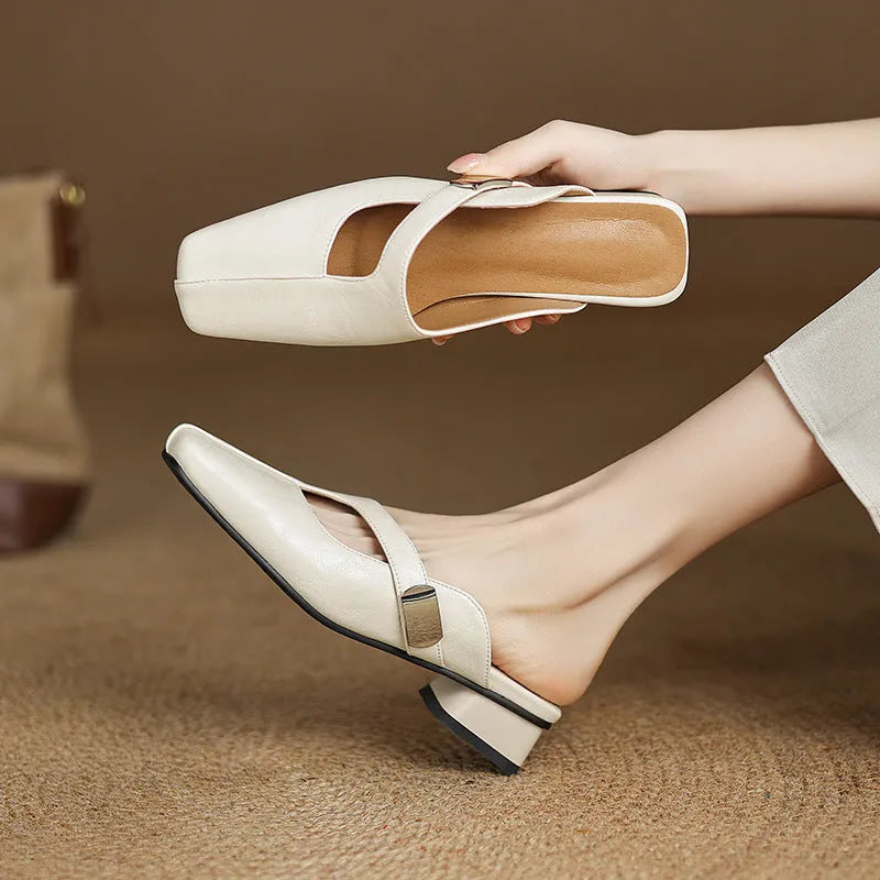 A pair of casual square-toe low-heel slippers in a solid colour on a rubber sole.