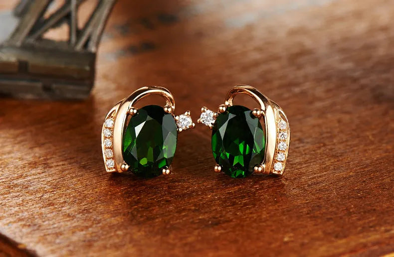 Pair of green ghost crystal stud earrings in silver with diamond-cut geometric shape on white background