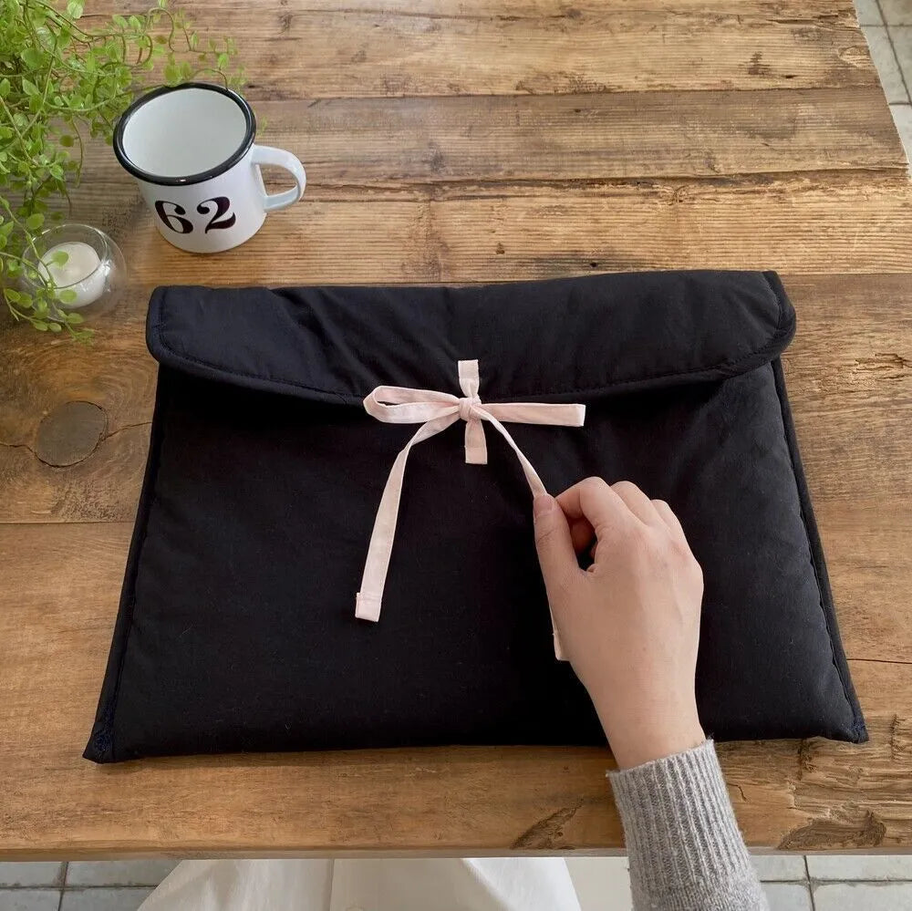 Women's black and white striped quilted laptop bag with a large ballet-style bow on the front.