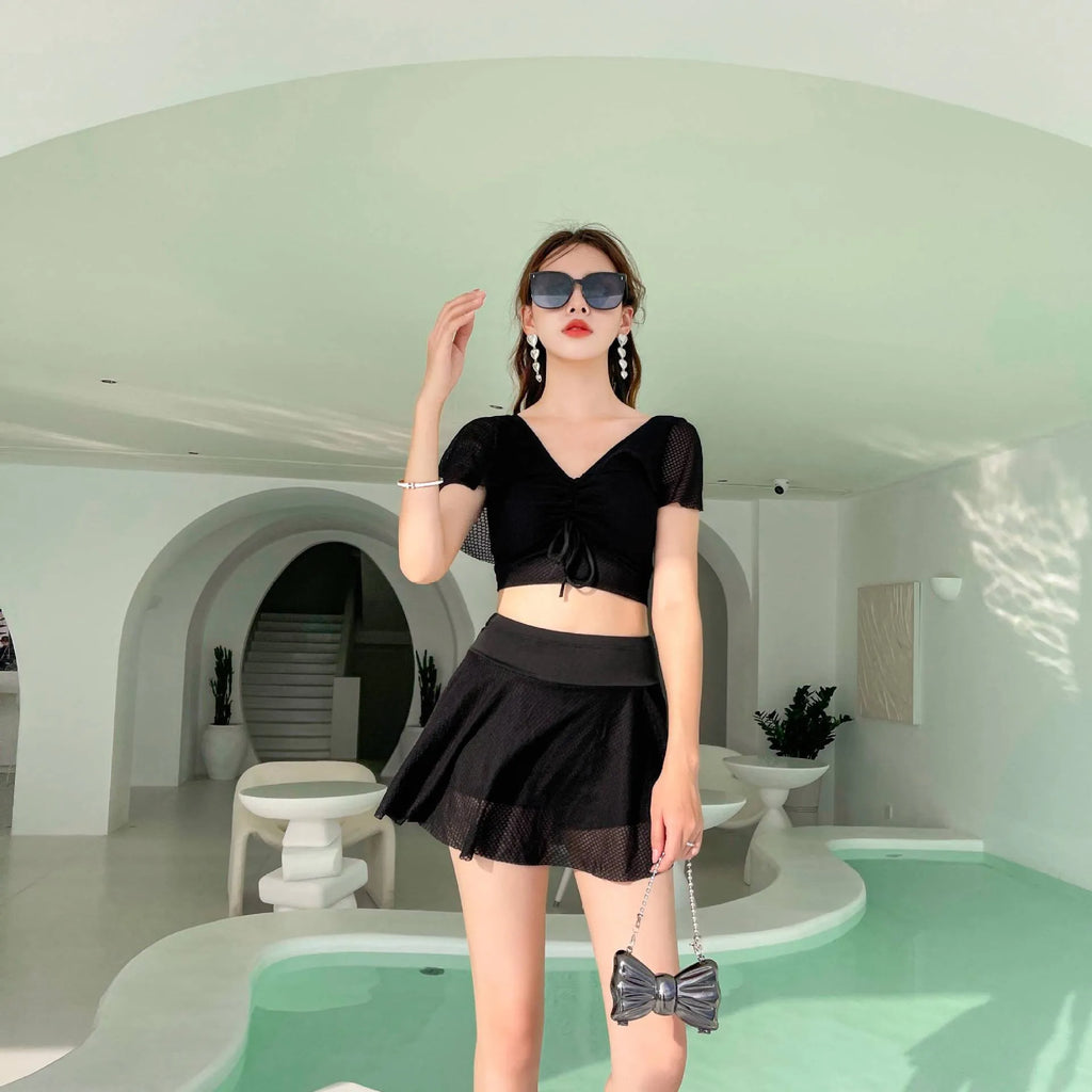 Women's solid colour two-piece swimsuit set with a top and split skirt.