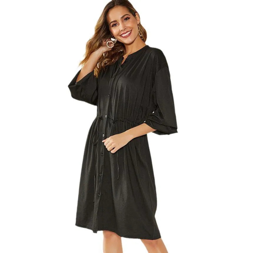 A women's loose black A-line dress with long sleeves, an elastic waist, and a cinched belt on a mannequin.