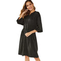 A women's loose black A-line dress with long sleeves, an elastic waist, and a cinched belt on a mannequin.